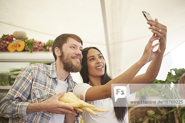 LÃ€chelndes Paar macht Selfie auf dem Bauernmarkt