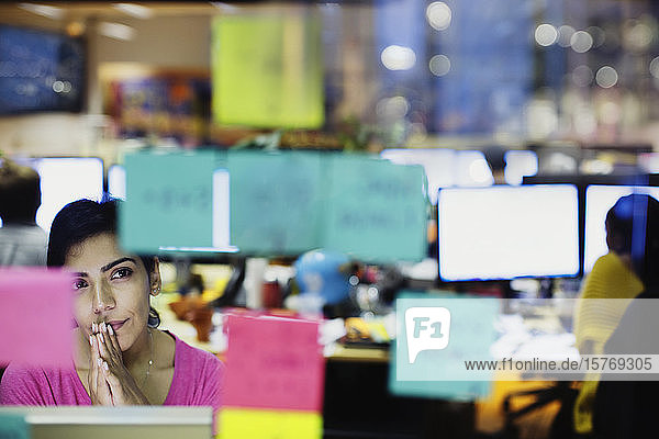 Thoughtful businesswoman looking at adhesive notes planning in office