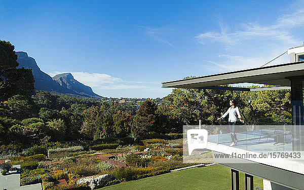 Frau auf sonnigem  modernem Luxusbalkon mit Blick auf Garten und Berge  Kapstadt  Südafrika