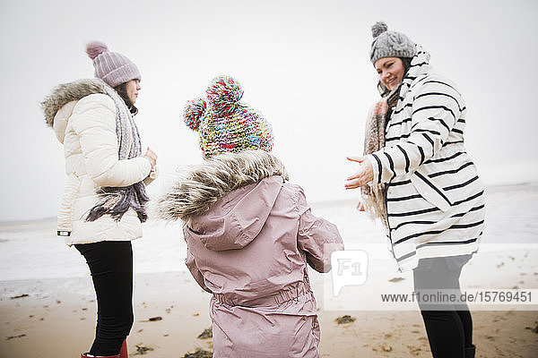 Familie in warmer Kleidung am winterlichen Meeresstrand