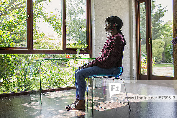 Gelassene junge Frau meditiert in einem ruhigen Büro zu Hause