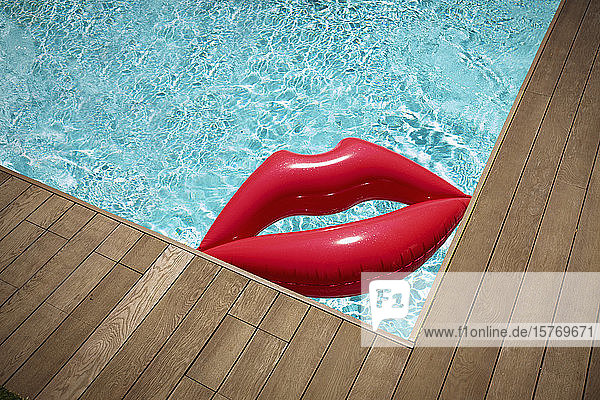 Aufblasbare Lippen schwimmen im sonnigen Sommerschwimmbad