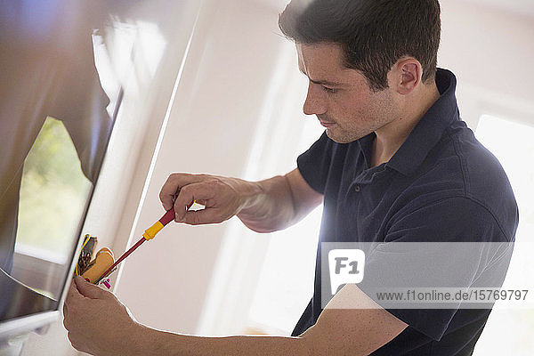 Electrician changing light fixture with tool