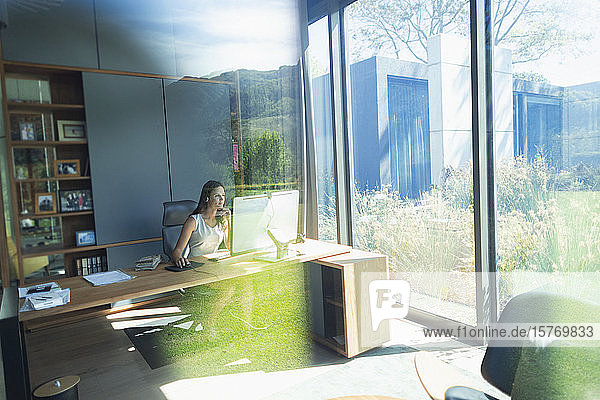 Geschäftsfrau arbeitet am Computer in einem sonnigen Heimbüro