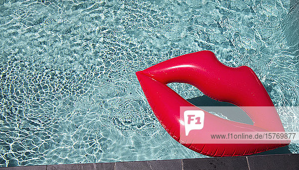 Aufblasbare Lippen schwimmen im sonnigen Sommerschwimmbad