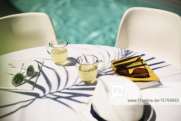 Tea and sunglasses on sunny poolside table