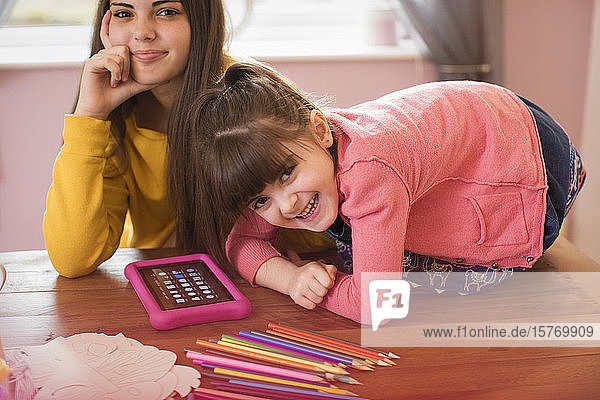 Porträt glückliche Schwestern mit digitalem Tablet auf dem Tisch