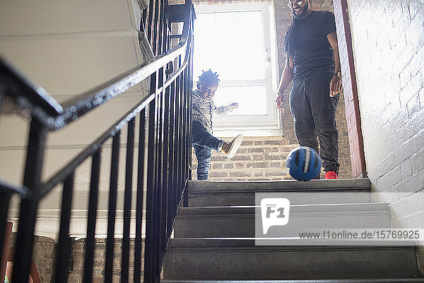 Vater und Kleinkind Sohn spielen mit Fußball auf Treppenabsatz