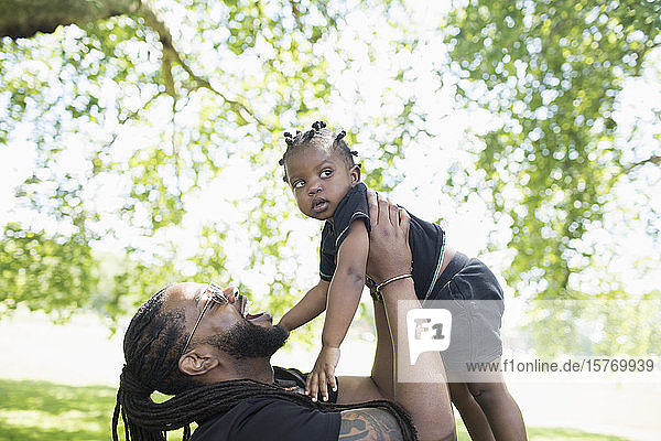 Verspielter Vater hält sein Kleinkind im Park