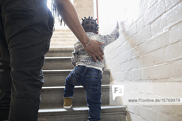 Vater hilft seinem kleinen Sohn beim Treppensteigen im Treppenhaus