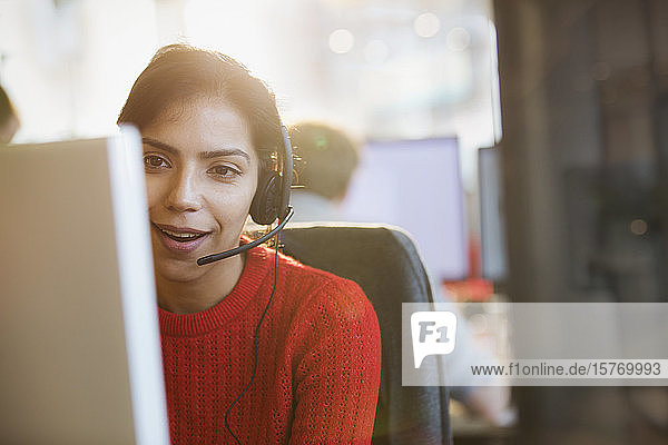Geschäftsfrau mit Headset bei der Arbeit am Computer im Büro