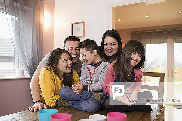 Portrait happy family with Down Syndrome child at dining table