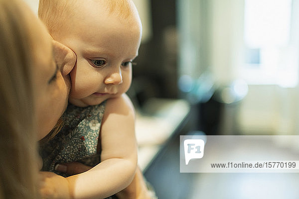 Close up mother kissing cute baby daughter