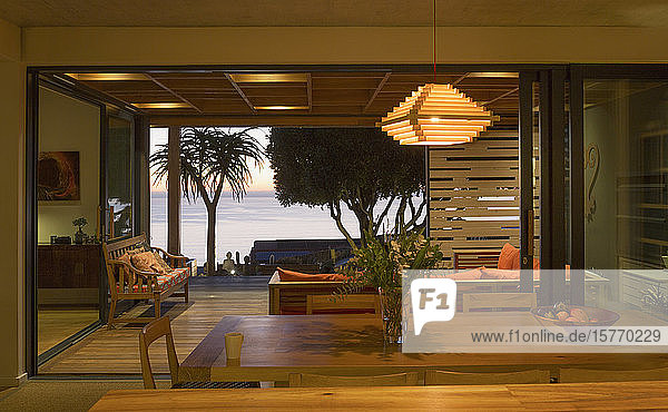 Beleuchtetes  modernes  luxuriöses Wohnhaus mit offenem Esszimmer zur Terrasse mit Meerblick
