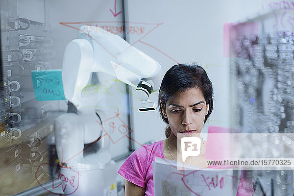 Female engineer with paperwork planning programming robotic arm