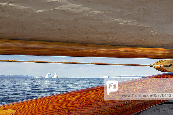 Blick auf Eisberge in der Ferne hinter dem hölzernen Segelbootmast Grönland