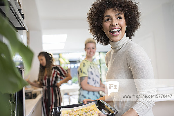 Glückliche junge Frau beim Kochen mit Freunden in der Küche