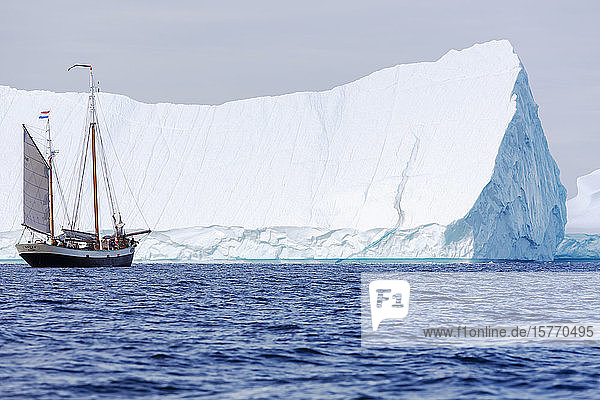 Schiff in der Nähe des majestätischen sonnigen Eisbergs auf dem Atlantik Grönland