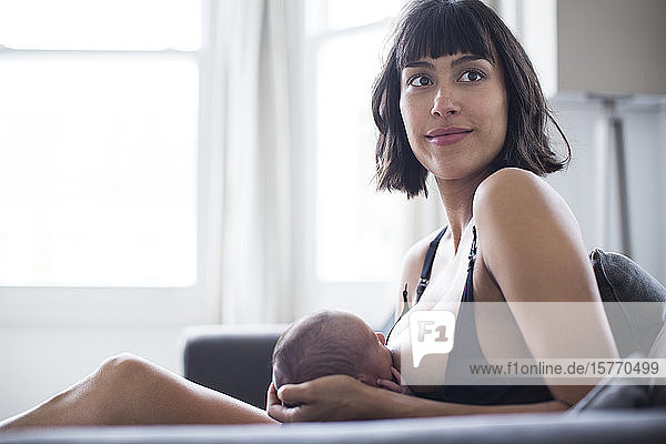Portrait schöne Mutter stillt neugeborenes Baby Sohn auf Sofa