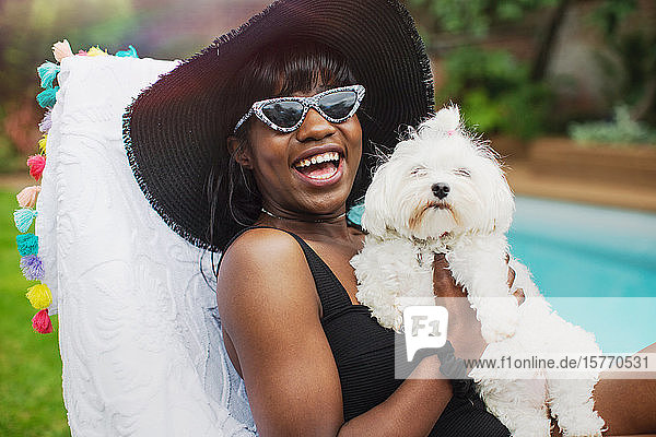 Portrait glückliche junge Frau mit Hund am Pool