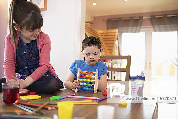 Konzentriertes Kind mit Down-Syndrom spielt mit Spielzeug am Tisch