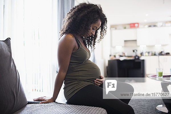 Gelassene junge schwangere Frau berührt den Bauch