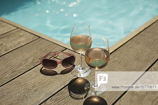 Rose wine glasses and sunglasses at sunny poolside