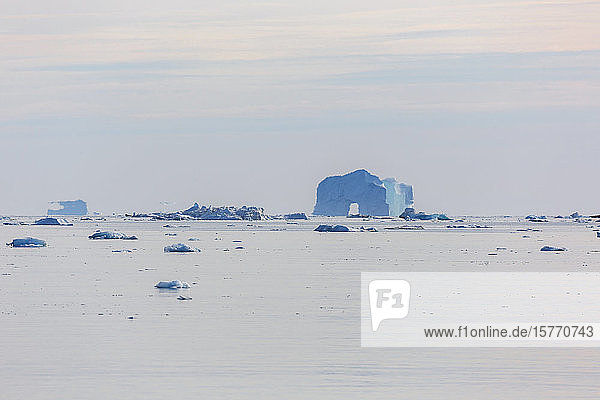 Majestätischer Eisbergbogen in der Ferne auf dem ruhigen Atlantischen Ozean Grönlands
