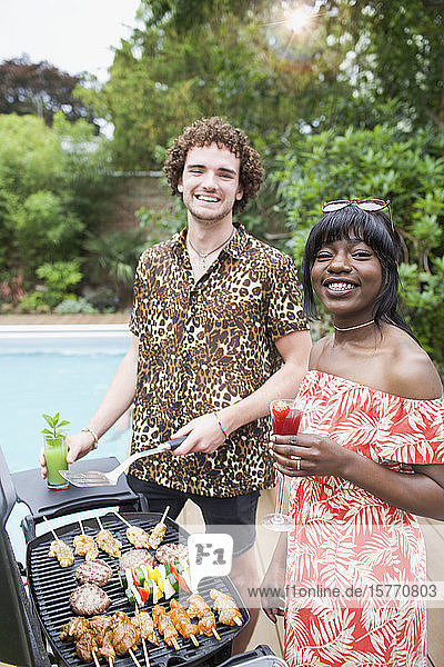 Portrait glückliches junges multiethnisches Paar beim Grillen am Pool