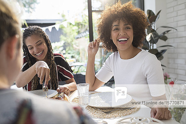 Glückliche junge Freundinnen beim Mittagessen am Esstisch