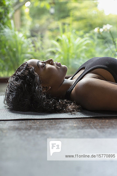 Serene young woman laying on yoga mat