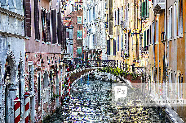 Paar umarmt sich auf einer bogenförmigen Fußgängerbrücke über einen Kanal  bunte Gebäude auf beiden Seiten; Venedig  Italien