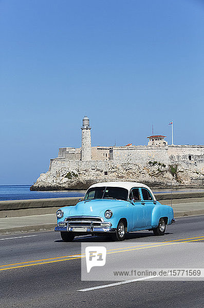 Old classic car on the Malecon Castillo del Morro (background); Havana Cuba