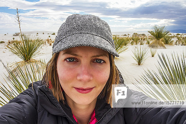 Young woman taking a self-portrait with desert plants and white sand in the background White Sands National Monument; Alamogordo New Mexico United States of America