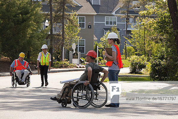 Arbeitsteam auf einer Straße mit zwei behinderten Arbeitern in Rollstühlen