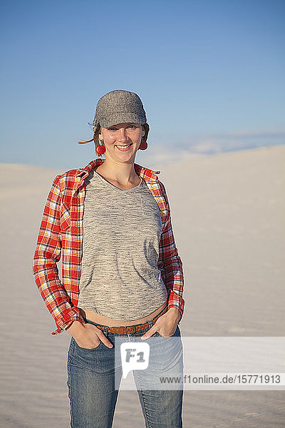 Portrait of a young woman standing on the white sand with blue sky White Sands National Monument; Alamogordo New Mexico United States of America
