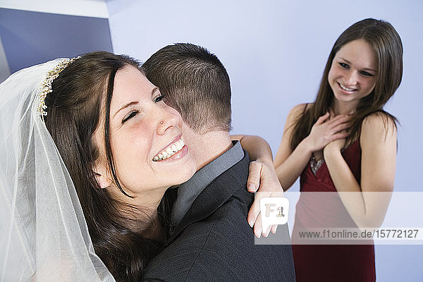 Blick auf eine fröhliche Braut  die ihren Bräutigam umarmt.