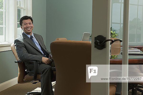Geschäftsmann sitzt an einem Konferenztisch an seinem Arbeitsplatz