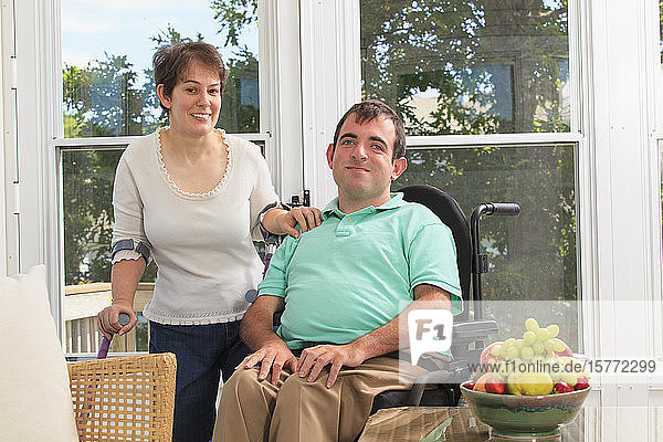 Porträt eines jungen Paares mit Behinderungen  eine Frau mit Mobilitätshilfen und ein Mann im Rollstuhl