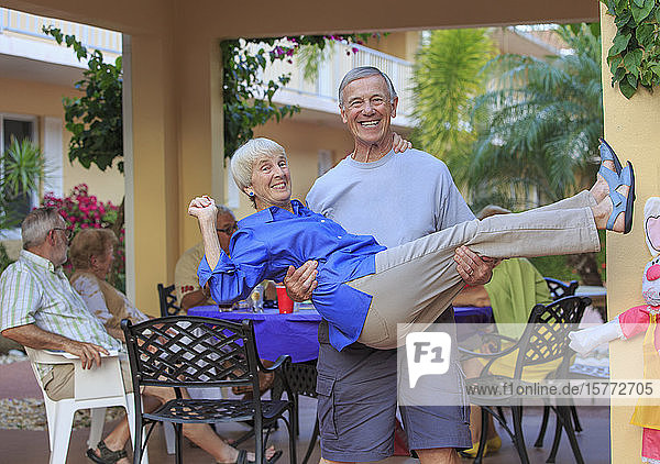 Ein lebenslustiges älteres Paar  der Mann hält die Frau und lächelt in die Kamera