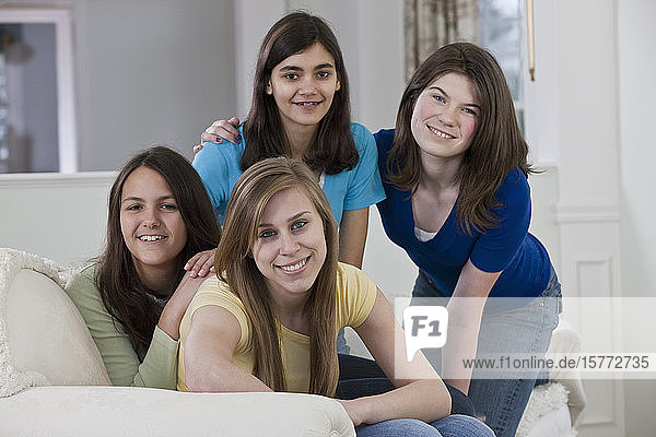 Porträt von vier Mädchen im Teenageralter  die zu Hause auf einer Couch sitzen