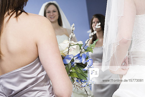Bride with her bridesmaid looking in a mirror.