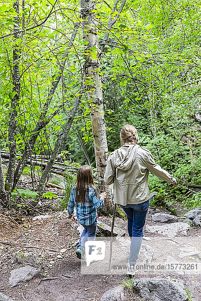 Zwei Schwestern gehen auf einem Waldweg; British Columbia  Kanada