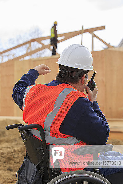 Mann im Rollstuhl benutzt ein Walkie-Talkie auf einer Baustelle