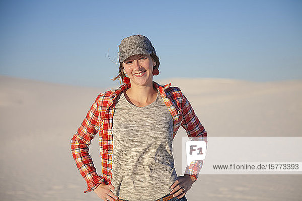 Portrait of a young woman standing on the white sand with blue sky White Sands National Monument; Alamogordo New Mexico United States of America