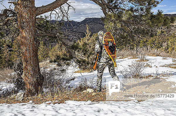 Jäger mit Tarnkleidung  Gewehr und Schneeschuhen bei einem Winterspaziergang im Hinterland; Denver  Colorado  Vereinigte Staaten von Amerika