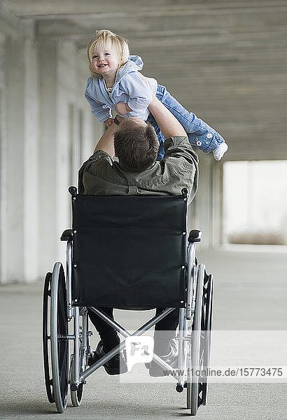 Mann im Rollstuhl spielt mit Baby