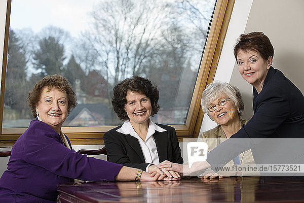 Portrait of smiling business women sitting by a table.