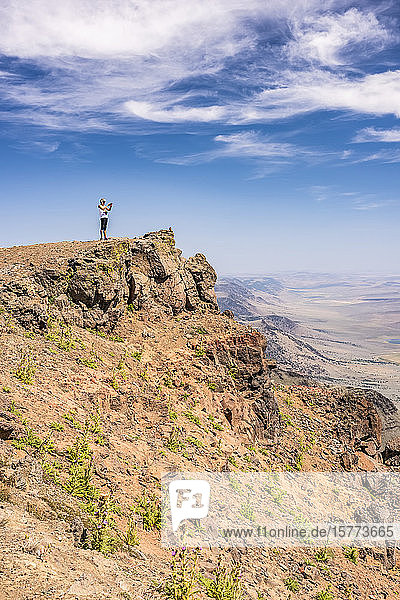 Eine Frau blickt von einem Felsvorsprung am Steens Mountain über die Alvord-Wüste  Südost-Oregon; Frenchglen  Oregon  Vereinigte Staaten von Amerika