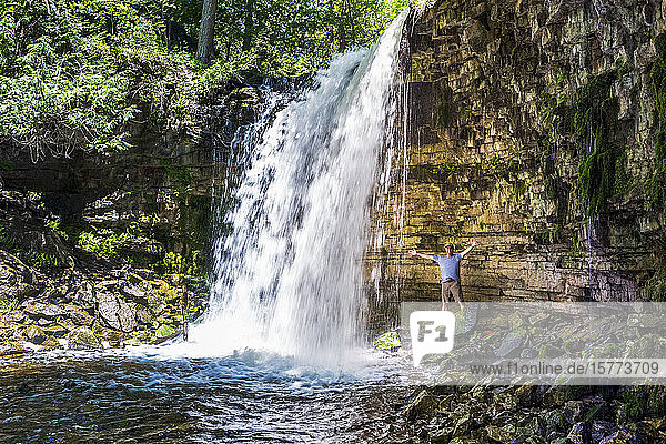 Male hiker inside a waterfall along the cliff bed  North of Burlington; Ontario  Canada